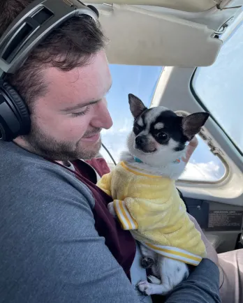 small white dog and man in airplane cockpit